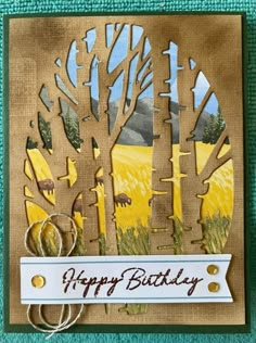 a birthday card with trees and mountains in the background, on a green surface that says happy birthday