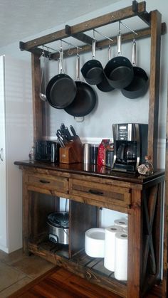 pots and pans are hanging on the wall above an old wooden table with drawers