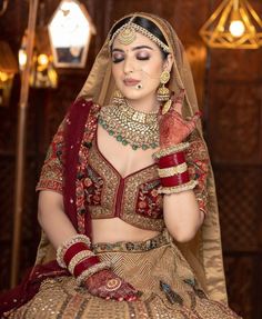 a woman in a red and gold bridal outfit with jewelry on her neck, wearing a