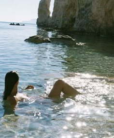 two people are in the water near rocks