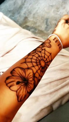 a woman's arm with a spider web and flowers tattoo design on the wrist