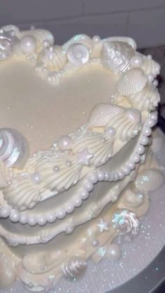 a heart shaped cake with shells and pearls on it's sides, sitting on top of a table