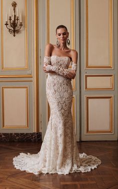 a woman in an off the shoulder wedding dress standing on a wooden floor with her arms crossed