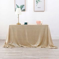 a table with a gold cloth on it and two pictures hanging above the table in front of it