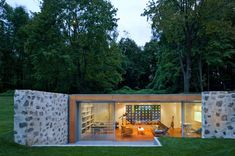 an outdoor living area with stone walls and grass in the foreground, surrounded by trees