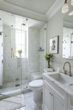 a white bathroom with a toilet, sink and shower stall is pictured in this image