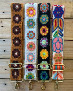 three different colored belts hanging from hooks on a wooden wall with wood planks in the background