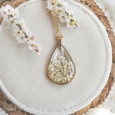 a necklace with white flowers on it sitting on a round table next to a basket