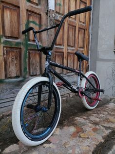 a black and white bicycle with red rims parked in front of an old building