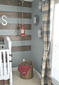 a baby's room decorated in gray and white with striped walls, plaid curtains, and a teddy bear basket