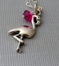 a silver necklace with a pink stone in the shape of a flamingo on it