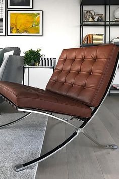 a brown leather chair sitting on top of a wooden floor next to a gray rug