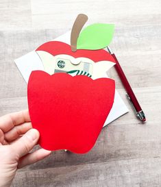 someone is holding an apple cut out from paper