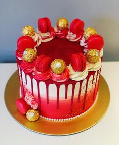 a red and white cake with gold decorations on it's top is sitting on a table