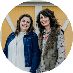 two women standing next to each other in front of a building