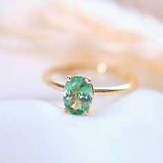 This solitaire ring features a vibrant oval green tourmaline, securely held in a classic 4-prong setting on a delicate 14k gold band. Material: Solid 14-karat gold Gold Colors: Yellow, rose, or white gold Main Gemstone: Oval green tourmaline, 8 x 6 mm Setting: Classic 4-prong Band Width: 1.75 mm A timeless and elegant piece that brings a pop of color to any occasion. Green Oval Sapphire Promise Ring, Classic Oval Green Sapphire Ring, Classic Green Oval Sapphire Ring, Green Oval Sapphire Ring With Center Stone, Classic Green Sapphire Oval Ring, Classic Oval Tourmaline Jewelry, Oval Solitaire Emerald Ring In 14k Gold, Oval Tourmaline Emerald Ring In Yellow Gold, Oval Sapphire Ring In 14k Gold For May Birthstone