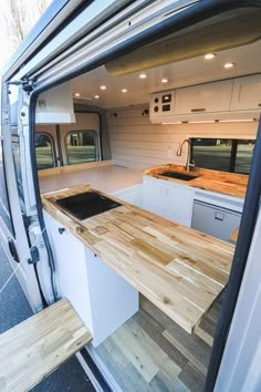 the interior of a camper van with wood flooring and counter tops in place