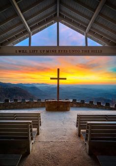 the inside of a church with benches and a cross in front of it at sunset