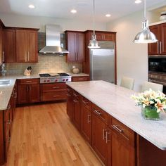 a large kitchen with wooden cabinets and white counter tops, along with a center island