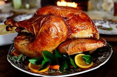 a roasted turkey on a plate with oranges and greens