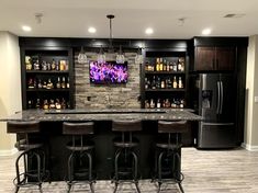 a bar with four stools in front of it and a television on the wall