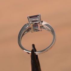 It is a lab alexandrite ring. The main stone is 7 mm*9 mm emerald cut.weight about 2.71 carats. The basic metal is sterling silver and plated with rhodium. To change the metal to a solid gold (white/rose) or platinum is also available, please ask for a quotation if you want. You can also go to my shop Home for more elegant rings: https://www.etsy.com/shop/godjewelry?ref=hdr_shop_menu Alexandrite is June birthstone . More alexandrite rings: https://www.etsy.com/shop/godjewelry?section_id=20715043 Wedding Rings Emerald Cut, Alexandrite Ring, Alexandrite Engagement Ring, Emerald Engagement Ring Cut, White Gold Wedding Rings, Sterling Silver Engagement Rings, Peridot Ring, Silver Engagement Rings, Elegant Ring