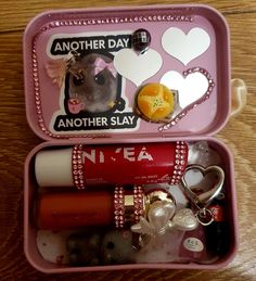 two pink containers with various items in them on a wooden table, one is empty and the other has an animal keychain