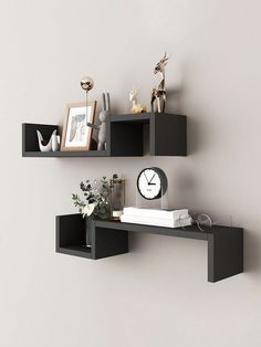 two black shelves with some pictures and a clock on top of one shelf next to the other