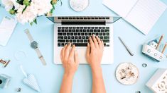 a person typing on a laptop surrounded by office supplies