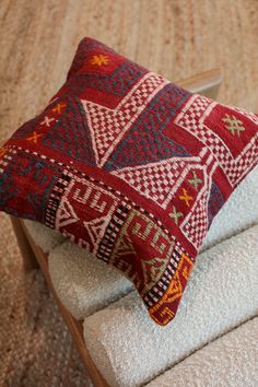 a red and blue pillow sitting on top of a white chair