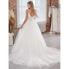 a woman in a white wedding dress looking down at her gown on the hanger