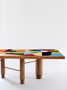 a wooden table with multicolored tiles on it's top and two legs