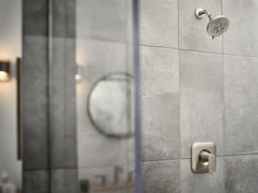 there is a shower head in the corner of this bathroom with grey tiles on the walls