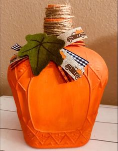 an orange pumpkin with a green leaf sitting on top of it's head and ribbon around its neck