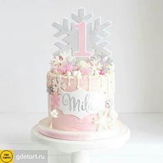 a pink cake with white frosting and flowers on top is decorated with a first birthday sign