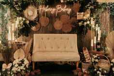 a couch sitting in front of a wooden wall with flowers and plants on top of it