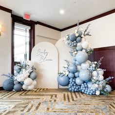 an arrangement of balloons and flowers on the floor in front of a sign that says baby shower