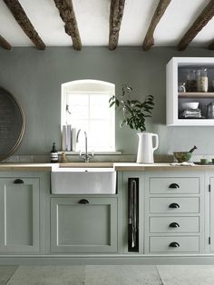 a kitchen with green painted cabinets and white counter tops, including a dishwasher