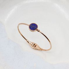 Lapis Lazuli d'Afghanistan, pierre précieuse de la royauté & de la spiritualité, favorisant calme et communication.
Pierre brute semi-précieuse sélectionnée de manière éthique, taillée et polie à la main avec savoir-faire
Monture unique en verre protégeant la pierre contre les chocs, chutes, coups, rayures, l'eau, et la chaleur.
Zircon serti sur le bracelet

TAILLE DU BRACELET :
Standard: 55 mm de diamètre de large - 2,2 pouces
Autres tailles disponibles sur demande :

Petit :  49 mm de diamètre de large - 1,9 pouces
Grand :  64 mm de diamètre de large - 2,5 pouces

SÉLECTIONNER LA MONTURE :

Acier inoxydable
Or Rose  18 carats plaqué
Or Jaune 18 carats plaqué
Rhodium Mat Noir  plaqué

SÉLECTIONNER LA PIERRE :

Lapis Lazuli avec de belles inclusions de pyrite et de calcite
Une rare Lapis Rose Gold Gemstone Bangle Jewelry, Blue Bangle With Polished Finish, Blue Fine Jewelry Bangle For Gifts, Gold Lapis Lazuli Bracelet With Gemstone, Gold Bracelets With Lapis Lazuli And Natural Stones, Gold Lapis Lazuli Gemstone Bracelet, Spiritual Sapphire Bracelet Jewelry, Luxury Sapphire Jewelry In Lapis Lazuli, Gold Lapis Lazuli Bracelets For Gift