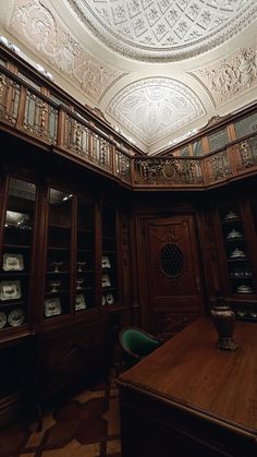 an ornately decorated room with wooden shelves and glass cases on the walls, along with a circular ceiling