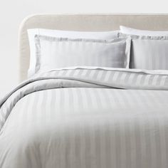 a bed with white and grey striped sheets