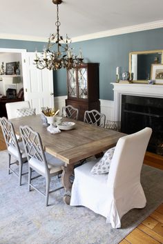 a dining room table with white chairs and a chandelier hanging from the ceiling