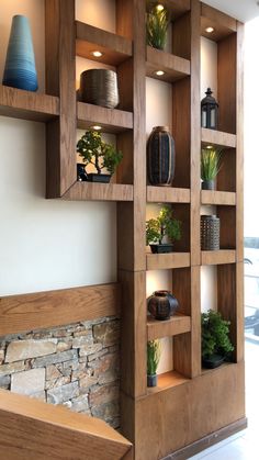 a wooden shelf filled with potted plants next to a stone wall