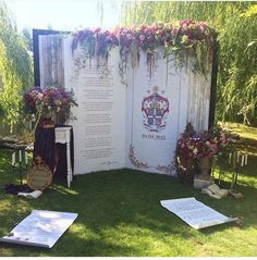 an outdoor ceremony setup with flowers and greenery on the wall, surrounded by other decorations