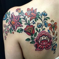 the back of a woman's shoulder with flowers and leaves on her left side