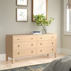 a bedroom with a dresser and pictures on the wall