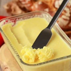 an ice cream in a glass container with a black spoon on the table next to other desserts