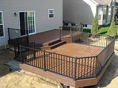 a wooden deck with metal railings in front of a house