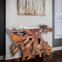 a wooden table with glass top in front of a painting on the wall above it