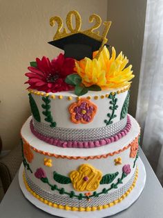 a three tiered cake decorated with flowers and a graduation cap